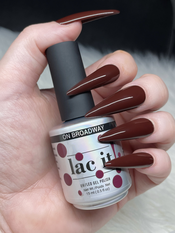 en Vogue Lac it! On Broadway burgundy UV/LED gel polish for professional nails and extensions shown on stiletto nails holding polish bottle